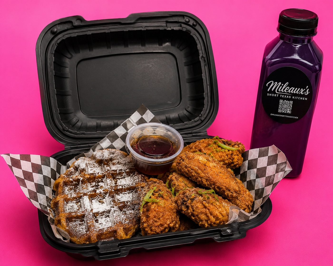 Hot honey maple wings and a Belgian waffle in a takeout box, with a bottle of purple lemonade, on hot pink